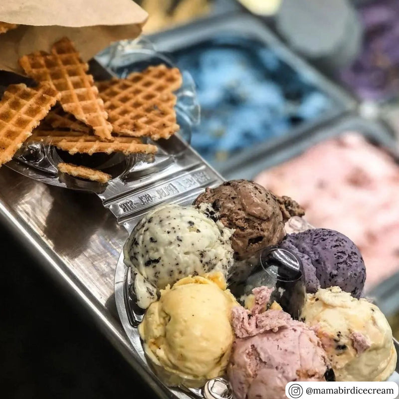 A 5-cell circular clear egg carton being used to hold scoops of ice cream and waffle cones