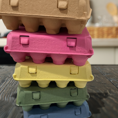 Stack of colorful vintage egg cartons in brown, pink, yellow, green, and blue.