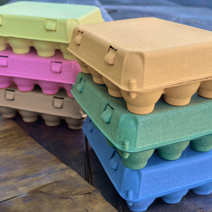 Stacked egg cartons in various colors on a wooden surface